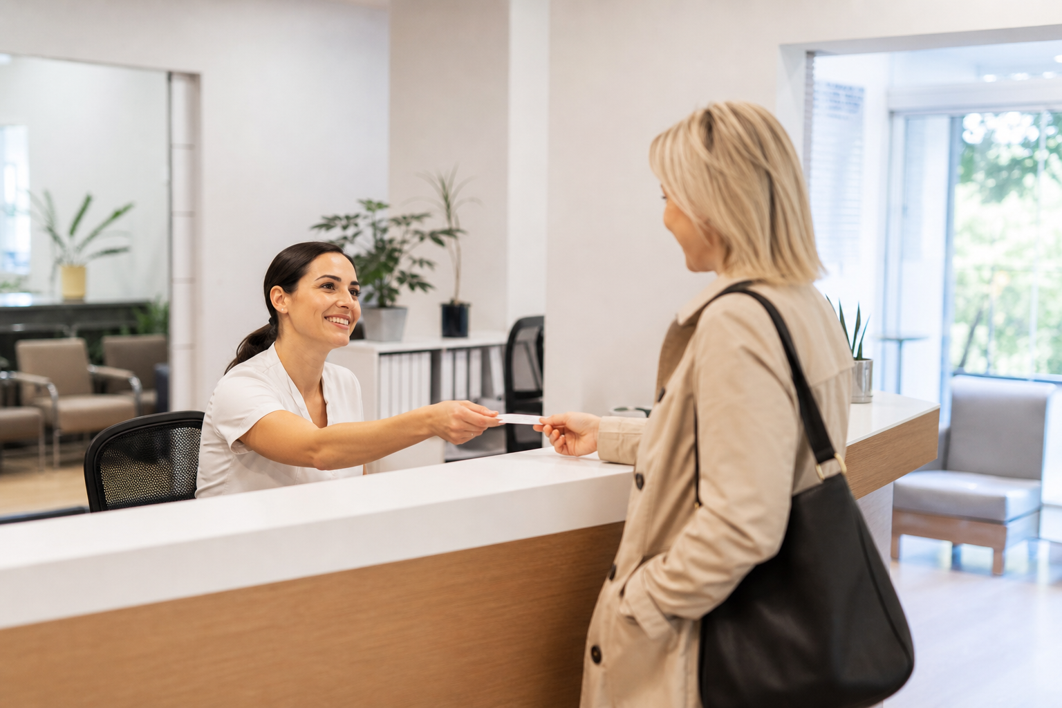 Clinic receptionist helping a visitor at the front desk